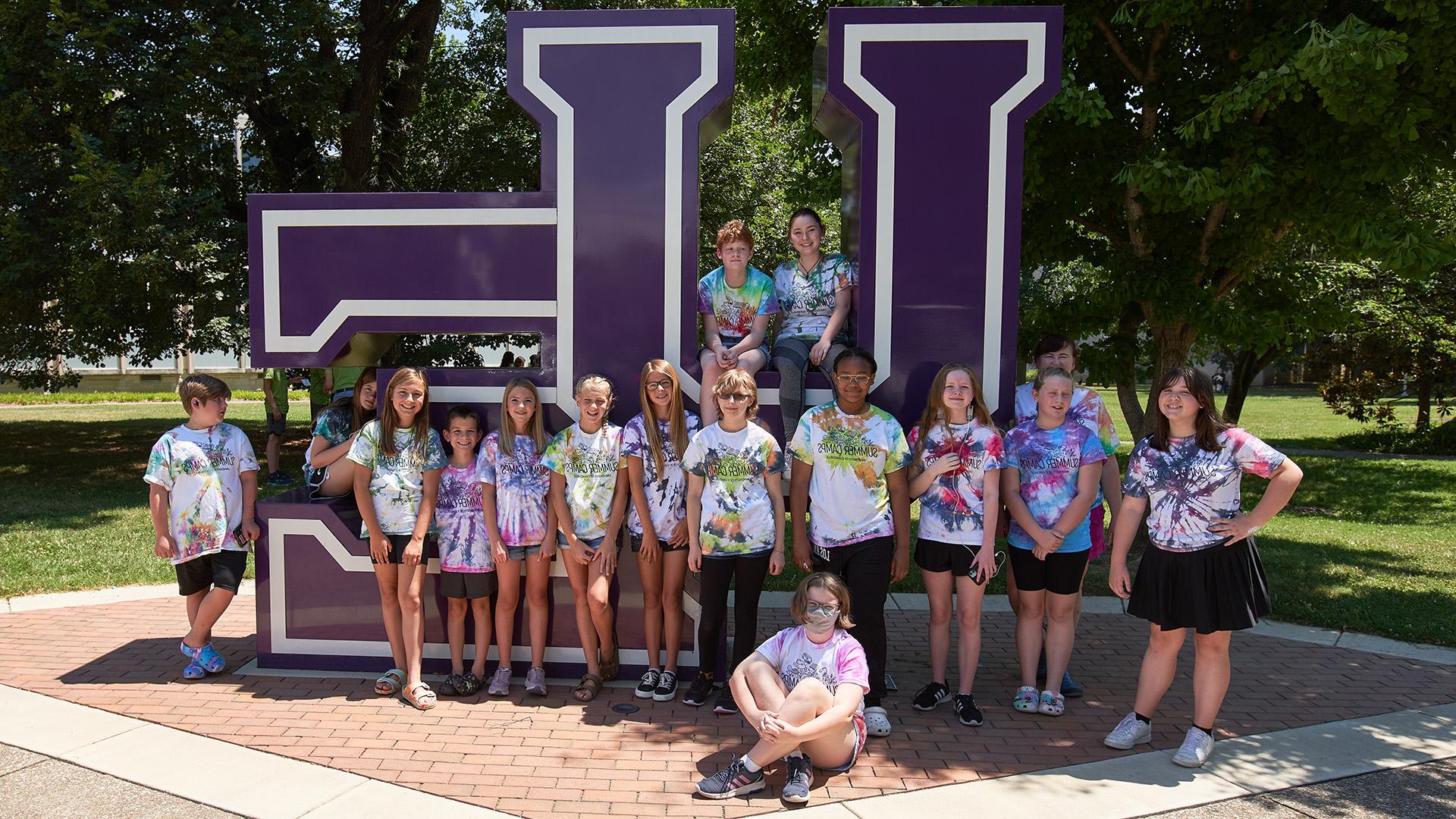 Art Camp students in front of UE letters sign